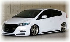 a white car parked in front of a wall with concrete floors and walls behind it