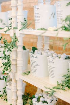 there are many cups on the shelves with greenery