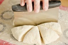 a person using a knife to cut dough into small pieces on a tablecloth with circles around it