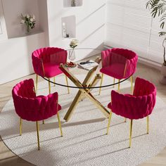 a round glass table with pink chairs and a white rug on the floor in front of it