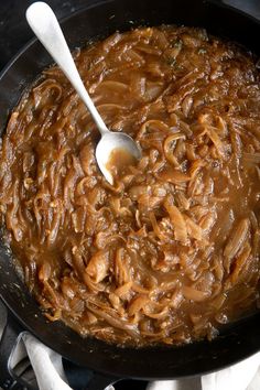 a skillet filled with noodles and sauce on top of a stove burner next to silverware