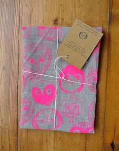 a piece of cloth with pink and grey designs on it sitting on a wooden floor