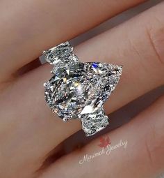 a woman's hand with an engagement ring on it and a large diamond in the middle