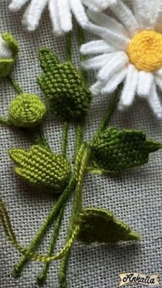 crocheted daisies and leaves on a piece of cloth