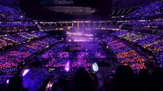 the stadium is lit up with purple and green lights