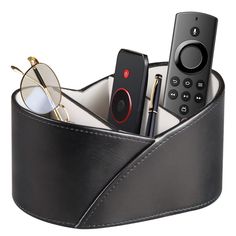 a black leather pen holder with glasses, remote control and other items in it on a white background