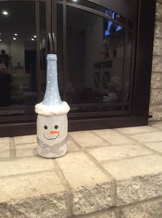 a bottle with a snowman hat on it sitting in front of a brick wall