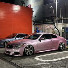 two cars parked next to each other in front of a building with red walls and an orange wall behind them