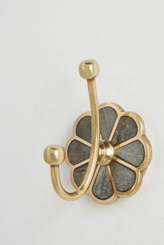 a close up of a flower shaped hook on a white wall with a gold finish