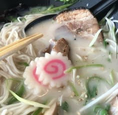 a bowl filled with noodles and meat next to chopsticks