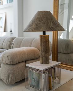 a living room scene with focus on the couch and mirror in the background as well as a birdcage