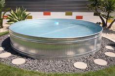 an outdoor hot tub in the middle of a garden with stepping stones on the ground