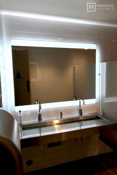 a bathroom with two sinks and a mirror above it that has lights on the wall