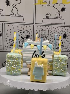 four decorated cakes sitting on top of a white cake plate with yellow and blue frosting