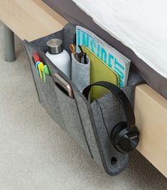 a bed with a gray storage bag on it's side and an open magazine holder in the middle