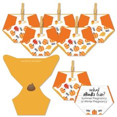 an orange and white paper cutout with clothes pins on it, hanging from clothes pegs