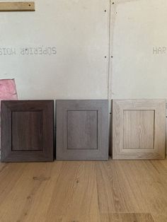 three different colored cabinets sitting next to each other on a hard wood floor in front of a white wall