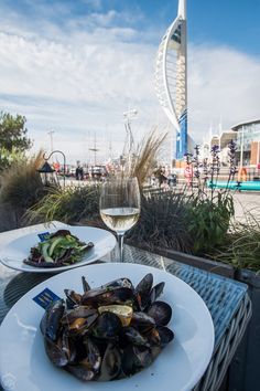 there is a plate of mussels and a glass of wine on the table