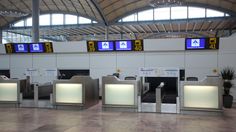 an airport terminal with several electronic check in counters