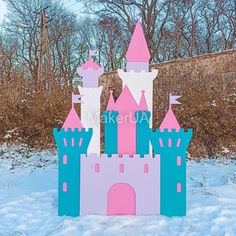 a pink and blue castle in the snow with trees in the backgroung