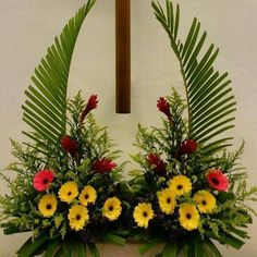 a cross with flowers and greenery in front of it