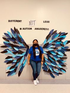 a woman sitting in front of a wall with blue wings