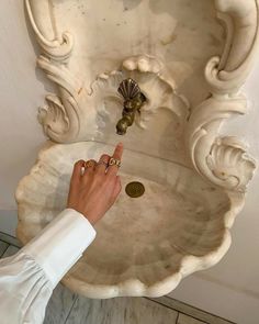 a person points at a coin in front of a sink