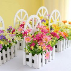 colorful flowers are placed in small white planters