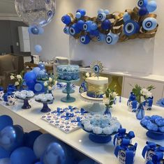 a table topped with blue and white desserts next to balloons in the shape of eyeballs