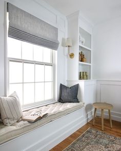 a window seat with pillows on it in a white room