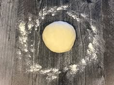 a ball of dough sitting on top of a wooden table covered in powdered sugar