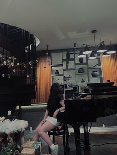 a woman sitting at a piano in front of a wall with lights and decorations on it