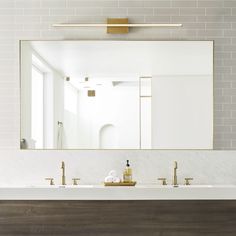 a bathroom sink with two faucets and a large mirror on the wall above it