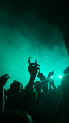 a crowd of people at a concert with their hands in the air and lights on