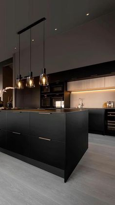 a large kitchen with black cabinets and lights on the counter top, along with an island