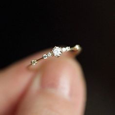 a person holding a tiny diamond ring in their hand