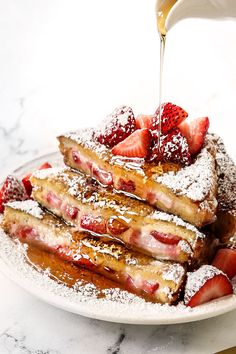 french toast with strawberries and powdered sugar being poured onto it