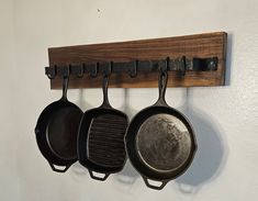 three cast iron skillets hanging on a wall