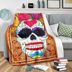 a blanket with a skull wearing sunglasses and flowers on it sitting in front of a couch