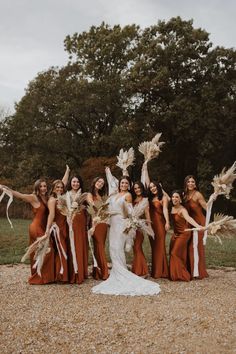 a group of women standing next to each other on top of a gravel field with trees in the background