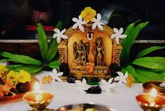 there is a small statue on the table with flowers and candles in front of it