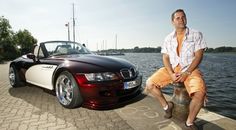 a man sitting on top of a fire hydrant next to a parked bmw car