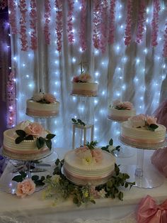 a table topped with three tiered cakes covered in frosting and pink flowers on top of it