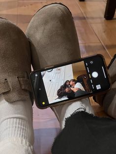 someone taking a selfie with their cell phone while sitting on the floor in front of them