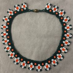 a beaded necklace with orange and white flowers