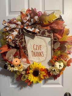 a wreath that says give thanks with sunflowers and leaves on the front door