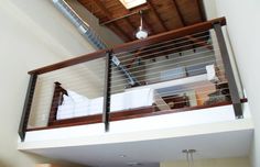 a balcony with metal railings and wood posts on the top floor, leading to an open living room