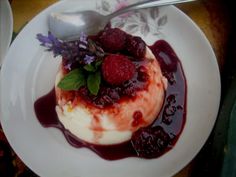 a white plate topped with dessert and berries on top of it next to a spoon