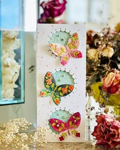 a close up of a greeting card on a table with flowers and vases in the background