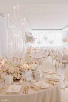 an elegant wedding reception with white and gold decor, candles and flowers on the tables